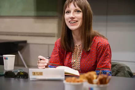 Prowadząca uśmiecha się do uczestników i uczestniczek.