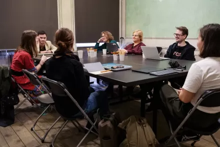 Uczestnicy i uczestniczki siedzą przy kwadratowym stole.