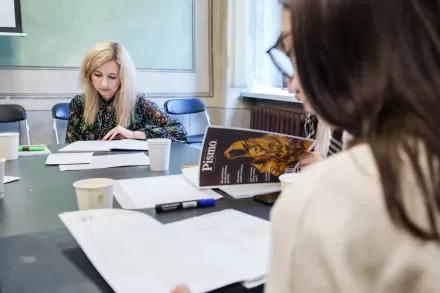 Dwie kobiety siedzą naprzeciwko siebie przy stole. Każda z nich czyta książkę.