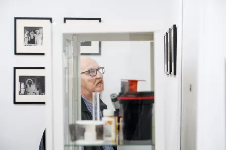 Starszy mężczyzna przygląda się czarno-białym fotografiom.