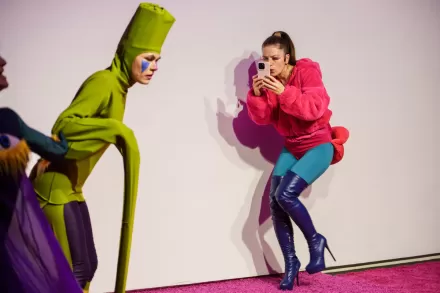 Jedna z aktorek przytula się do ściany i robi zdjęcie telefonem.