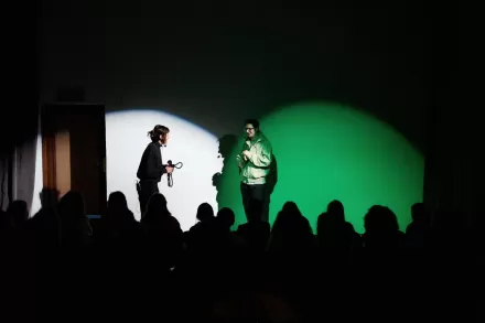 Dzieci oglądają spektakl. Występuje kobieta i mężczyzna, którzy razem rozmawiają. 