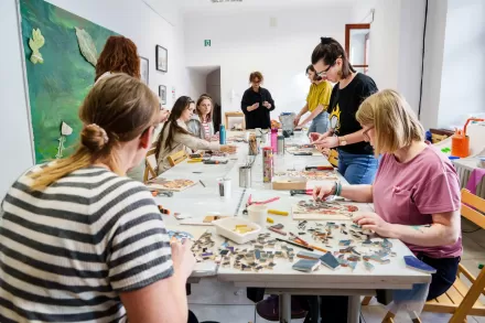 Przy stole pracują warsztatowicze i warsztatowiczki.