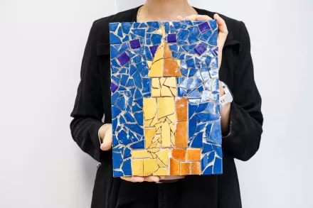 Kobieta prezentuje swoją mozaikę. Nie widać jej twarzy.