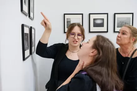 Kuratorka pokazuje na jeden z obrazów.