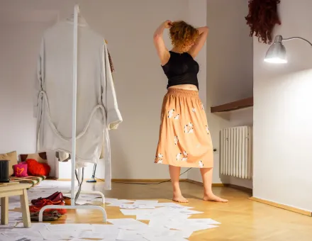 Artystka przebiera się w spódnicę i bluzkę.