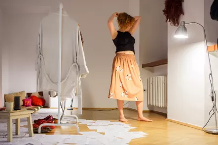 Artystka przebiera się w spódnicę i bluzkę.