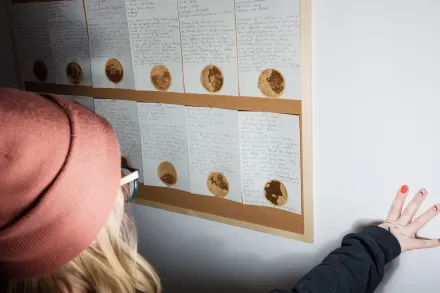 Kobieta czyta notatki na tablicy. To element wystawy.