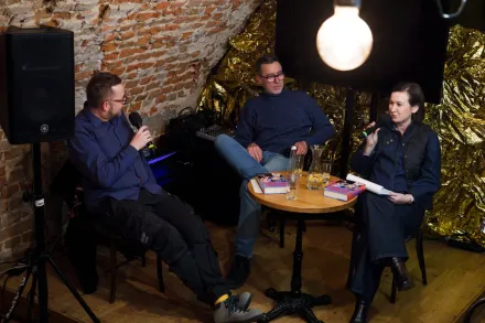 Dwoje prowadzących i autor książki rozmawiają przy stoliku. 