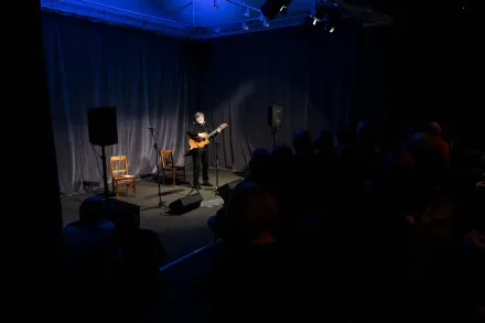 Mężczyzna śpiewa i gra na gitarze.