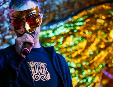 Mężczyzna śpiewa w masce na twarzy.