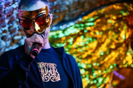 Mężczyzna śpiewa w masce na twarzy.