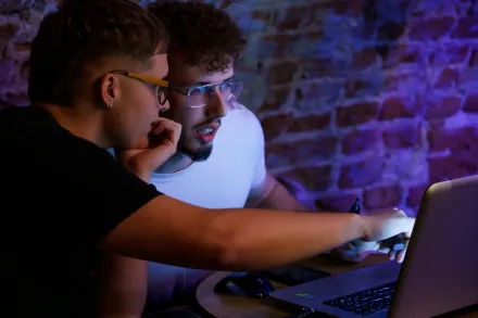 Dwaj chłopacy obsługują laptopa.