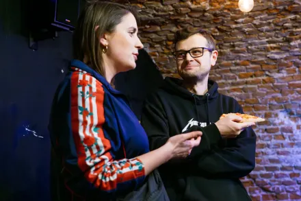 Kobieta rozmawia z mężczyzną, który je pizzę.