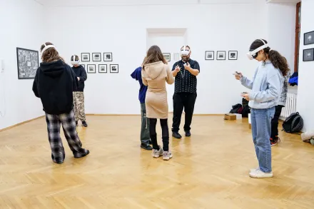 Ludzie chodzą po sali i oglądają wystawę w okularach VR.