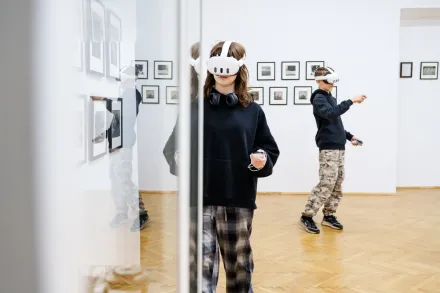 Ludzie chodzą po sali i oglądają wystawę w okularach VR.