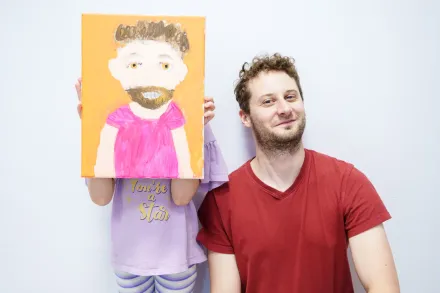 Dziecko trzyma swój obrazek. To portret prowadzącego warsztaty.