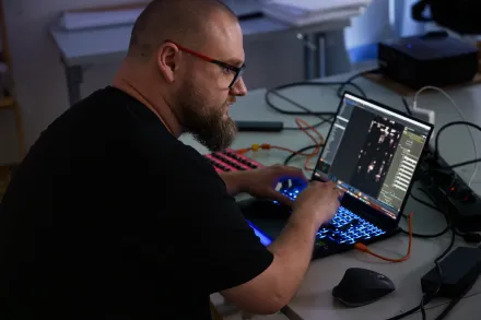 Mężczyzna coś programuje na laptopie. 