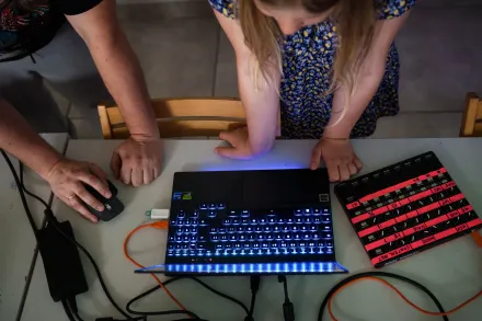 Zdjęcie od góry. Na stole leży laptop i dopięta do niego  klawiatura.