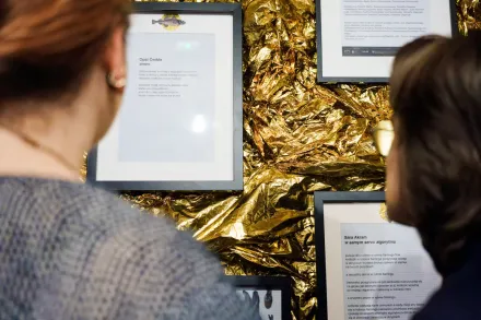 Dwie kobiety czytają wiersze zawieszone na ścianie.