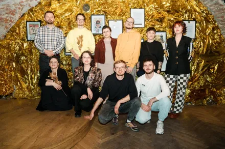 Grupa uczestników stoi na ścianie w kolorze złota.