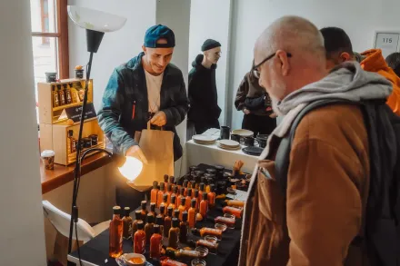 Mężczyzna stoi przy stoisku z ostrymi sosami.