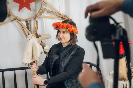 Mężczyzna robi zdjęcie kobiecie. Ma ona na głowie wianek i trzyma gwiazdę kolędniczą.