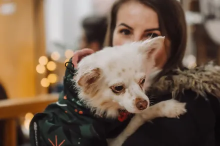 Kobieta trzyma na rękach psa.