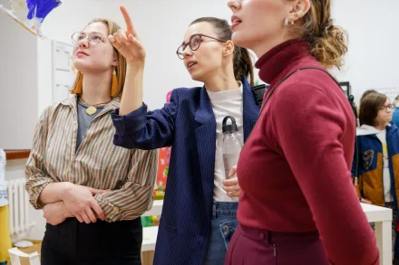 Trzy nastolatki coś sobie pokazują.