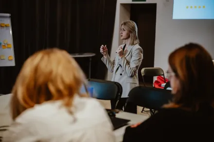 Prowadząca opowiada coś uczestnikom.