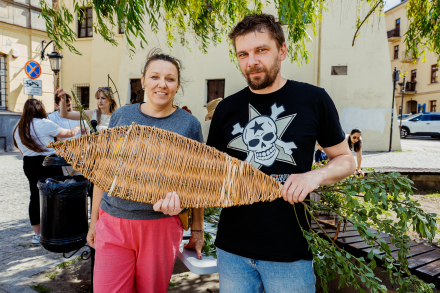 Kobieta i mężczyzna trzymają dużą rybę z wikliny.