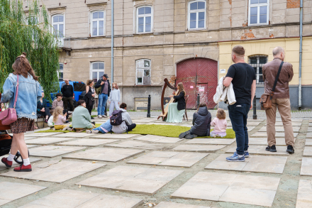 Publiczność słucha występu harfistki.