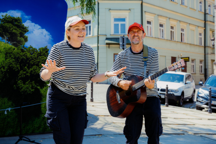 Kobieta się uśmiecha, a mężczyzna gra na gitarze.