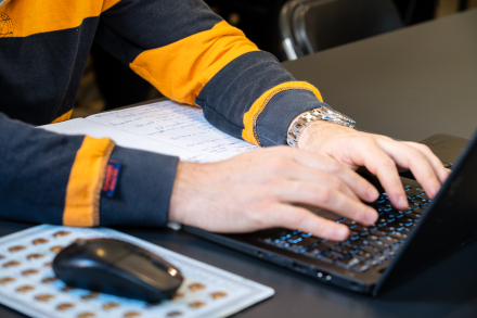 Uczestnik warsztatów trzyma ręce na klawiaturze laptopa. 