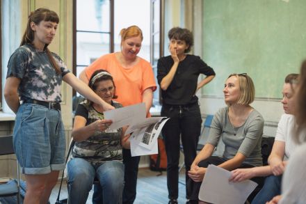 Kobiety siedzą w kole i oglądają zeskanowane zdjęcia.