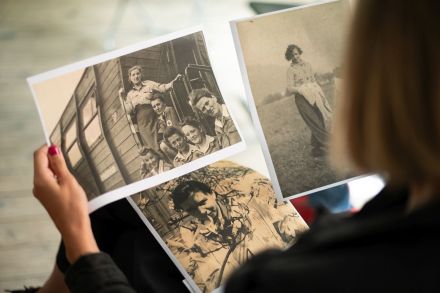 Kobieta ma na kolanach rozłożone skany trzech zdjęć.