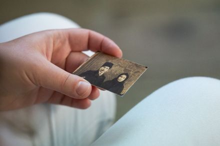 Kobieta trzyma w ręce małą czarno-białą fotografię.