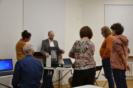 Uczestnicy spotkania stoją dookoła mężczyzny, który na skanerze prześwietla zdjęcie.