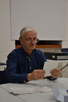 Mężczyzna w okularach przygląda się papierowym zdjęciom.