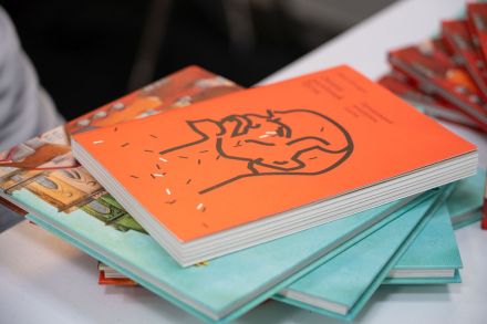 Książka z pomarańczową okładką leży na stosie innych