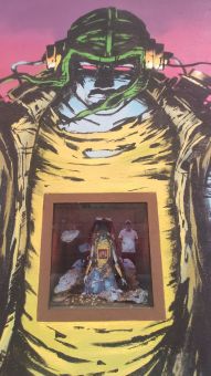 Mural przedstawia postać o niebieskiej skórze, w zielonej czapce z nausznikami, w żółtej koszulce z dziurą, kurtce oraz przyczepionymi przewodami do uszu i pleców. Na brzuchu postaci jest witrynka, w której jest jego mniejsza wersja klękająca na kolanach. 