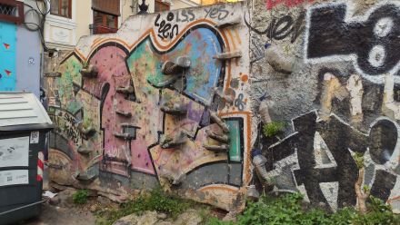Na murze z graffiti, są zawieszone doniczki zrobione z plastikowych dużych butelek. Zostały zawieszone  nierównolegle, jedna pod drugą, więc sprawiają wrażenie drabin. 
