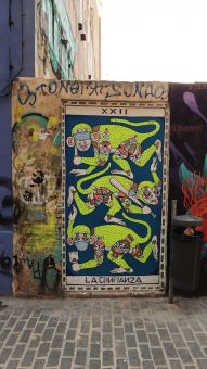 Mural przedstawia trzy zielone małpy z kolorowymi partiami ciała, które mają założone maseczki na różne sposoby. Pierwsza na górze ma maseczkę na oczach i trzyma w łapie nóż,  małpa pod spodem ma dwie maseczki włożone do uszu i trzyma kij baseballowy, natomiast  małpa na dole ma maseczkę założoną na usta i nos, a w łapie trzyma zbitą butelkę.