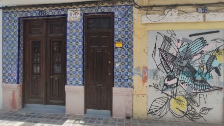 Wejścia do budynku są wyłożone wzorzystymi, niebiesko-białymi kafelkami. Obok wejść widnieje graffiti przedstawiające ptaka, niosącego gałązkę z cytryną.