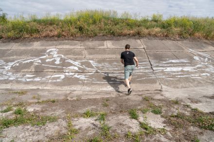 Mężczyzna wchodzi na zbocze, na którym widnieje mural namalowany białym sprayem.