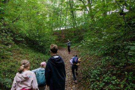 Dzieci idą wąwozem. Otacza je las.