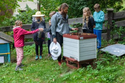 Pszczelarz pokazuje dzieciom ule.