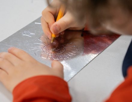 Dłonie dziecka, które odbija kwiatka przez kalkę.