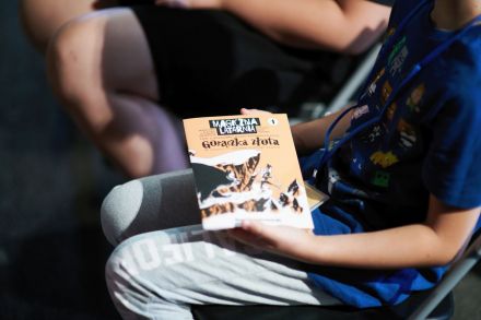 Chłopiec trzyma książeczkę reklamującą wydarzenie.