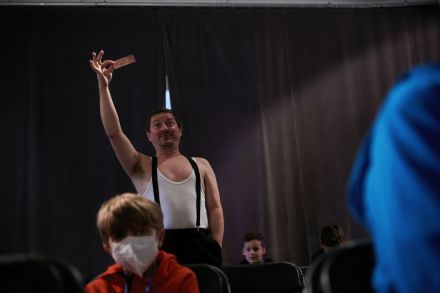 Aktor grający Charliego Chaplina macha do dzieci biletem.